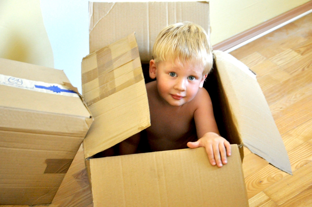 Blonde haired boy peaking out of moving box